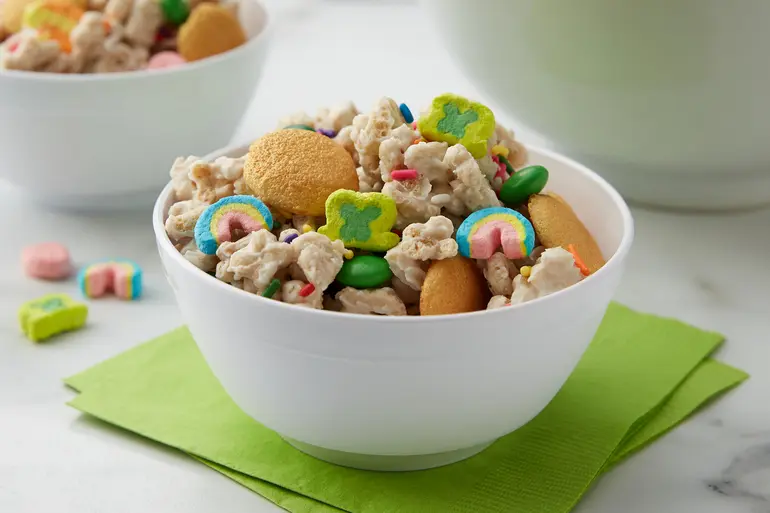Receta de Lucky Charms™ Leprechaun Gold Snack Mix mostrada en un bol encima de una servilleta amarilla.
