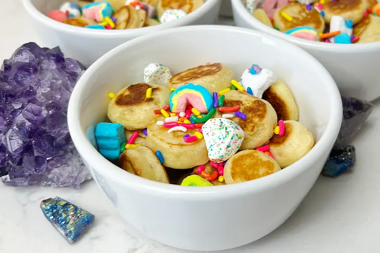 Un bol con Lucky Charms™ Magic Gems Mini Pancakes espolvoreados con cereales Lucky Charms Magic™ Gems.