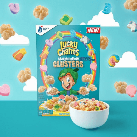 Una caja llena de Lucky Charms™ marshmallow clusters en frente de un fondo azul con nubes.