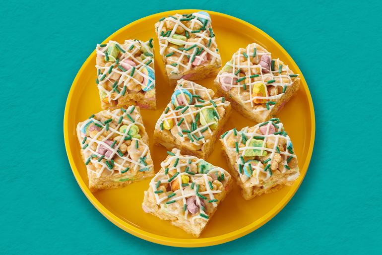 Siete barras de cereal de Lucky Charms Honey Clovers en un plato amarillo sobre un fondo verde.