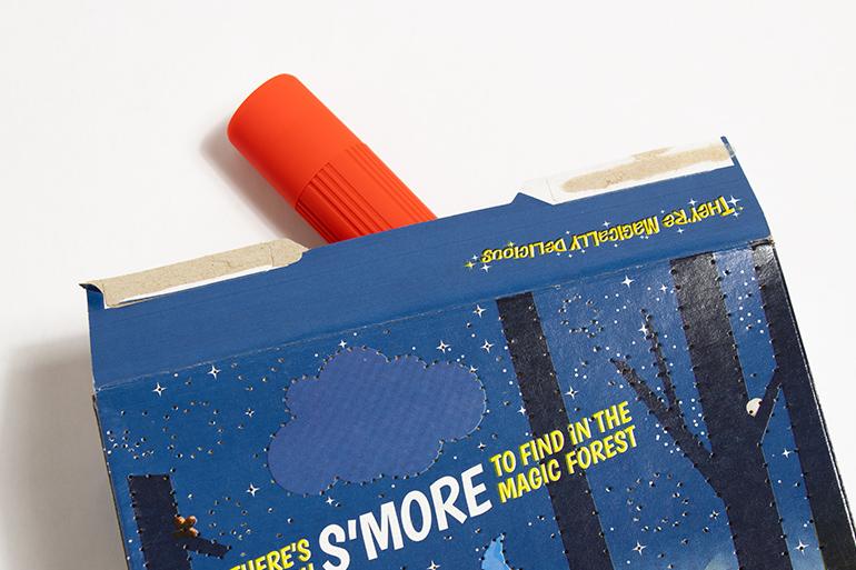 Vista por encima de un mantel individual hecho con una caja de cereales Lucky Charms™ bajo un bol de cereales y un vaso de zumo de naranja.