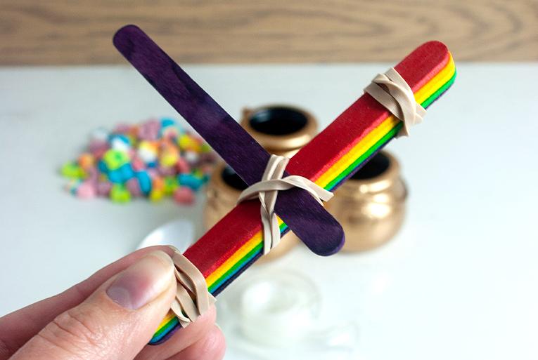 Step 2 of the catapult setup with jumbo craft sticks bound together by rubber bands.