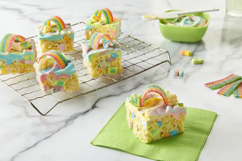 Lucky Charms™ Frosted Rainbow Cereal Bars served on a green napkin from a baking rack.