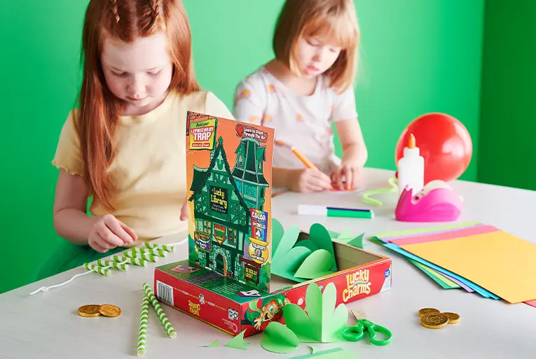 Lucky trap decorations being made by two girls with materials scattered about the table