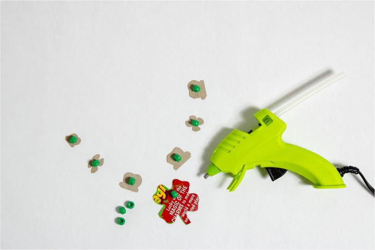 A green glue gun to put green beads on bits of a Lucky Charms cereal box.